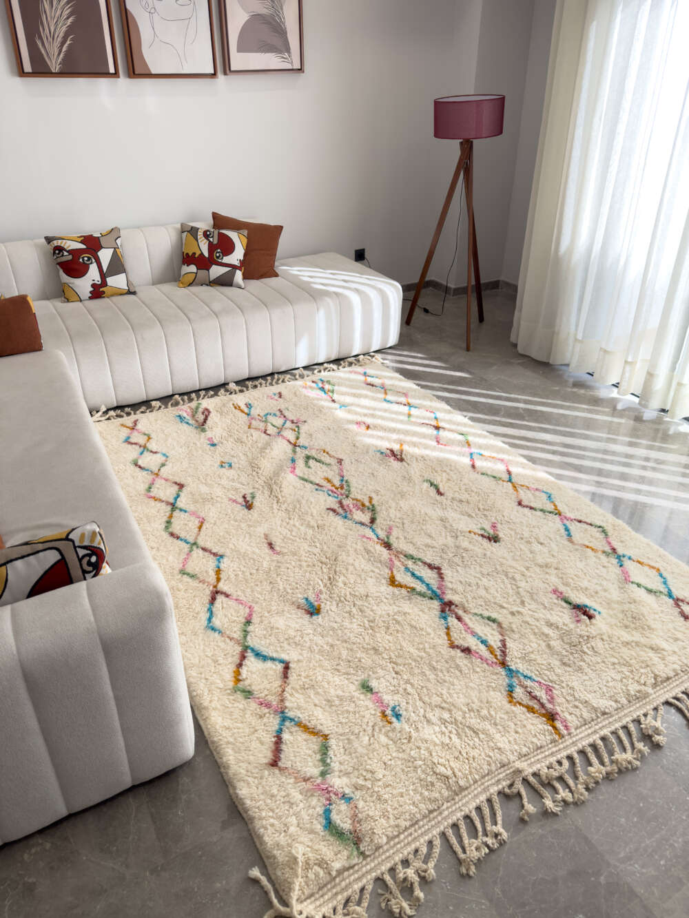 An ornate Moroccan rug featuring rich, contrasting colors and intricate geometric patterns, laid on a polished hardwood floor in a tastefully decorated room.